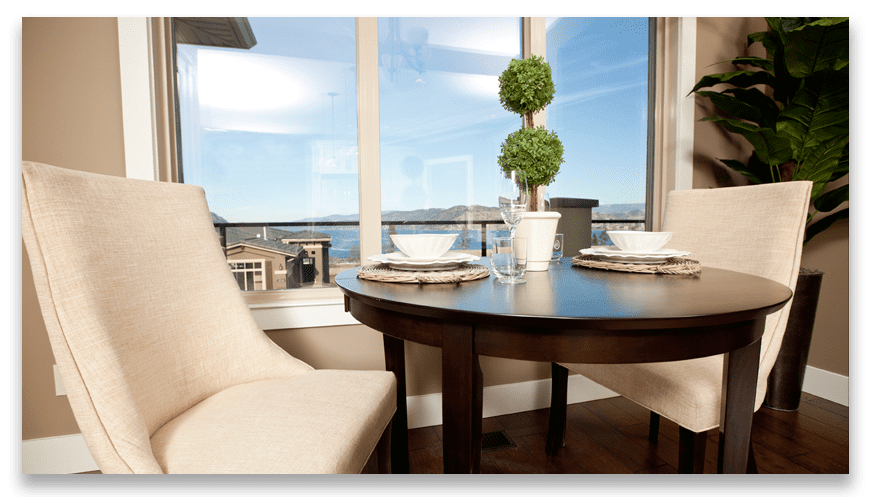 two tan chairs sat with table and houseplant with window overlooking west harbour