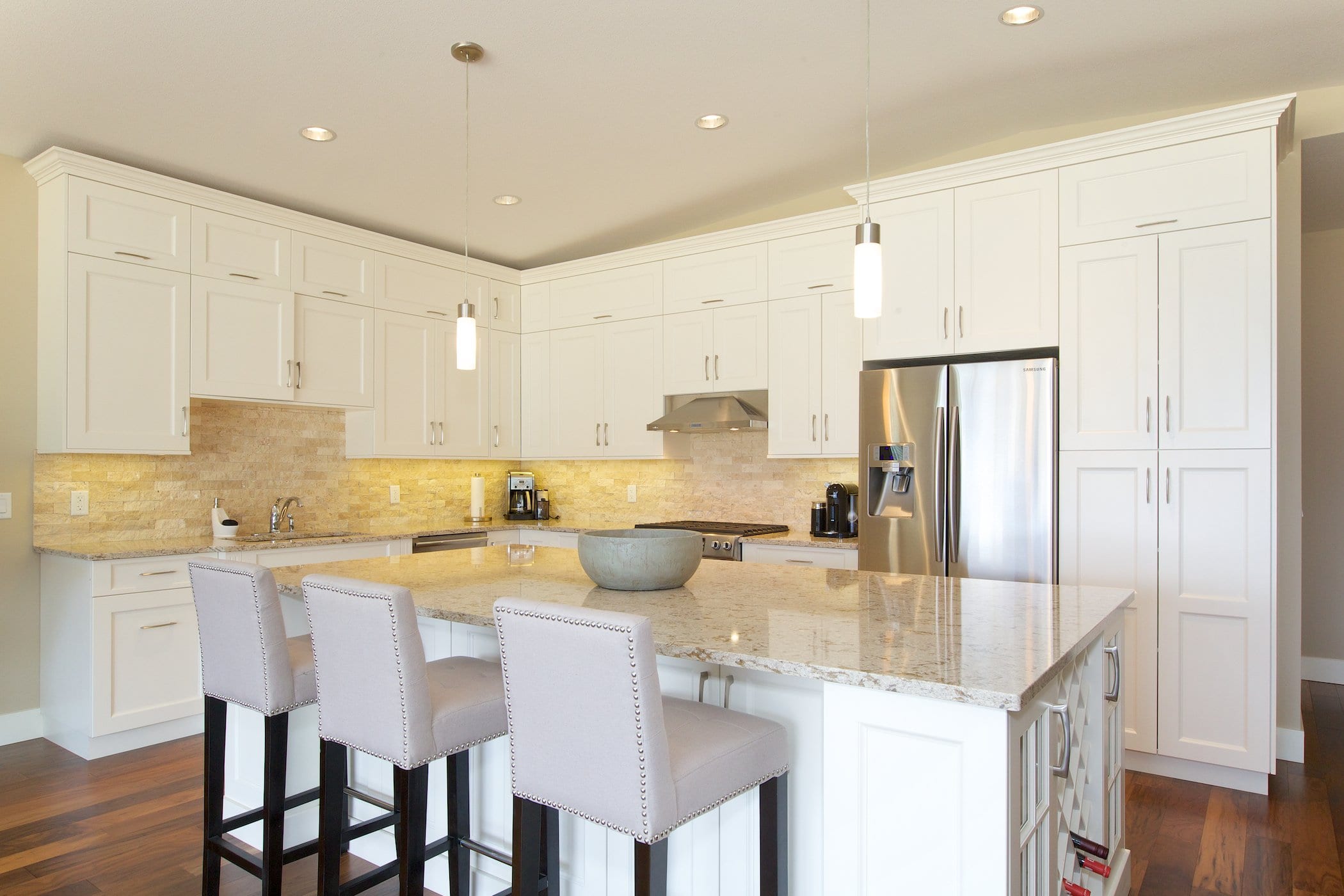 interior shot of west harbour home kitchen with white cabinetry bar chairs fridge and stove