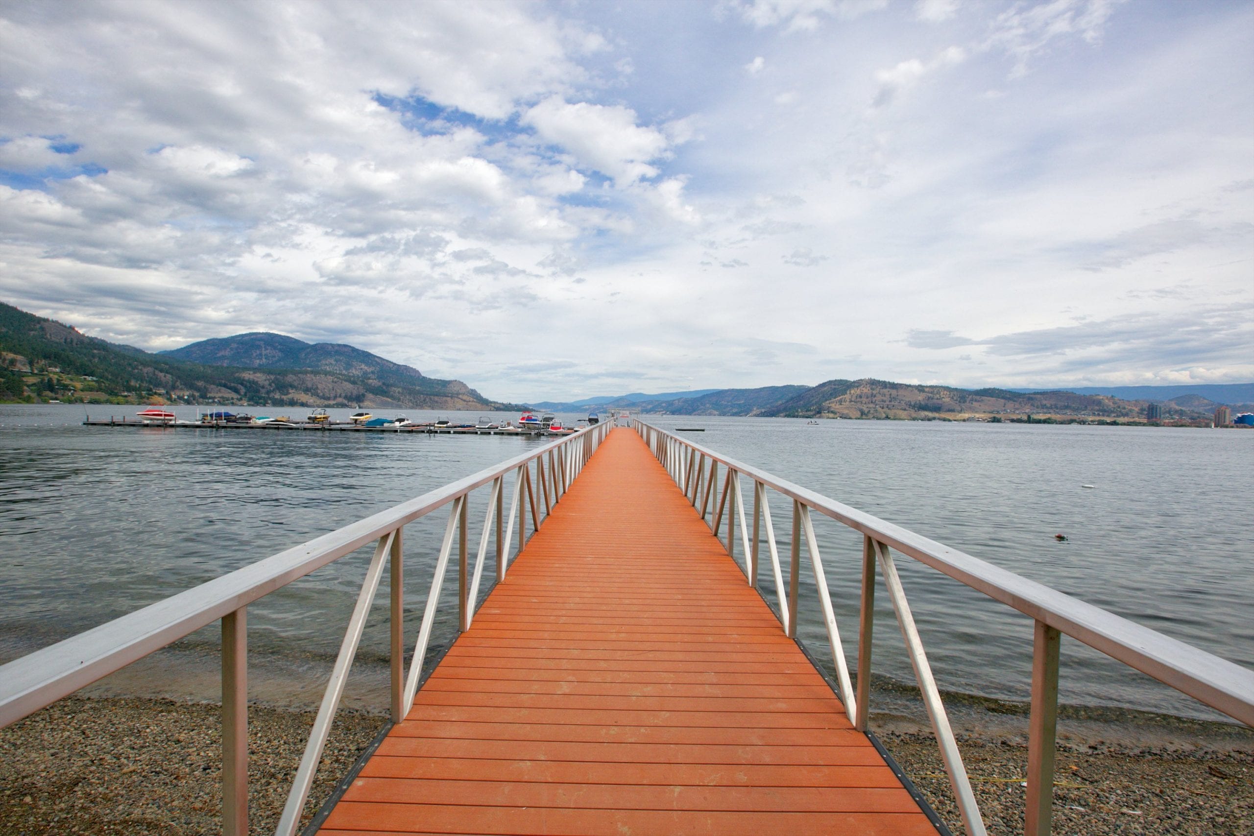 walkway shot staring directly at the marina on the okanagan lake with multiple boats parked