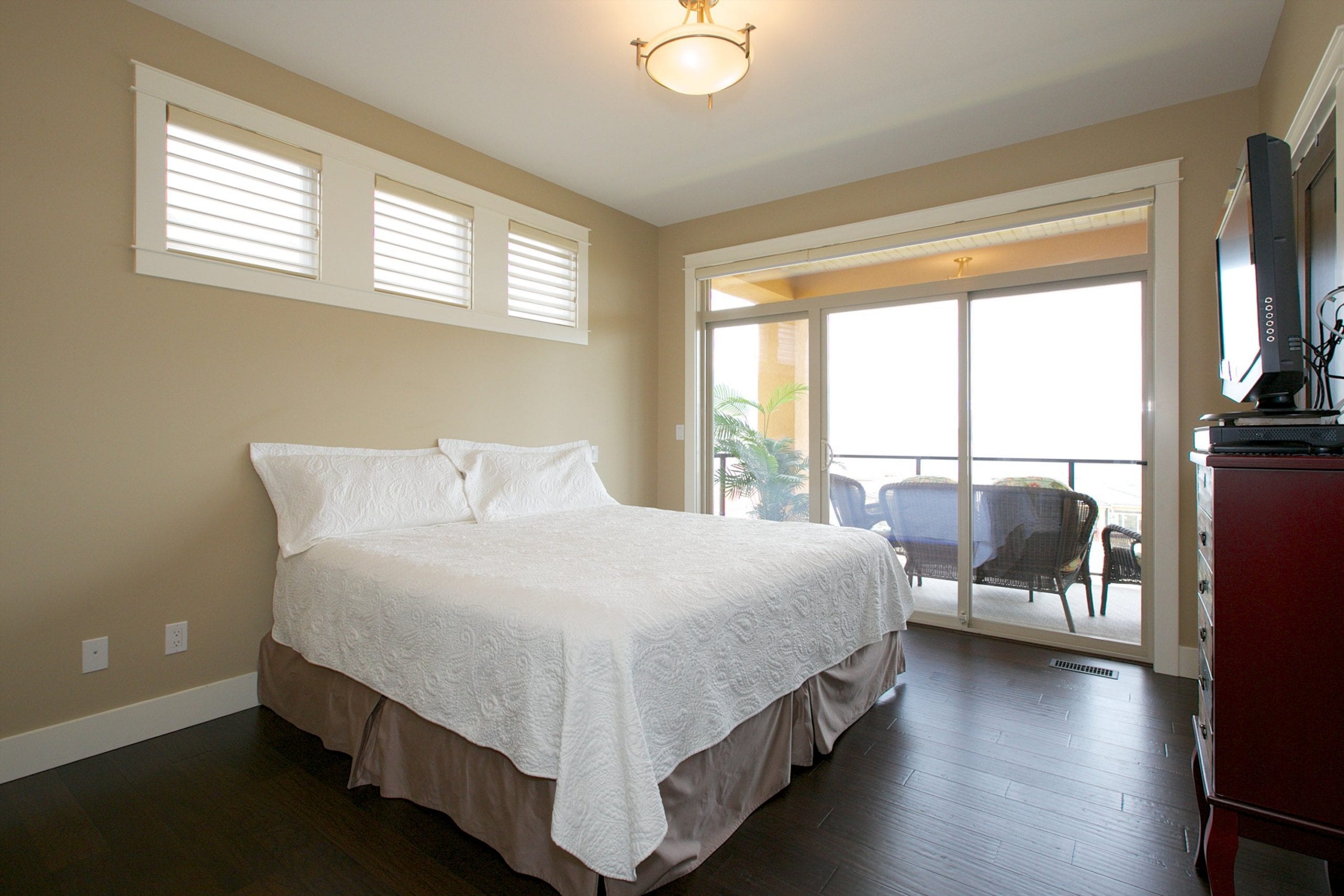 interior shot of west harbour home master bedroom with bed facing a television and four windows bringing in natural light