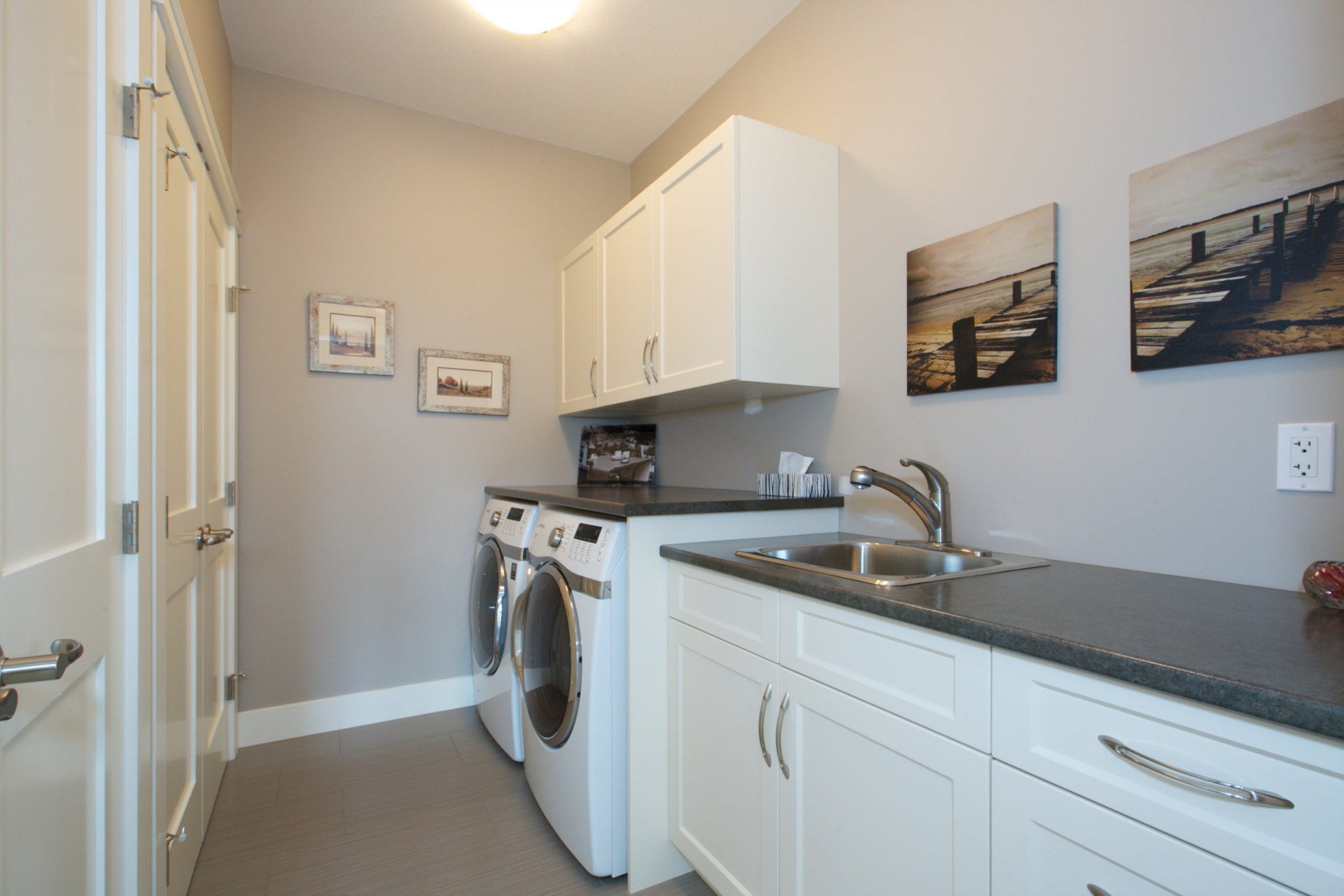 interior shot of west harbour home laundry featuring a sink with cabinetry both below and above a washer and a dryer
