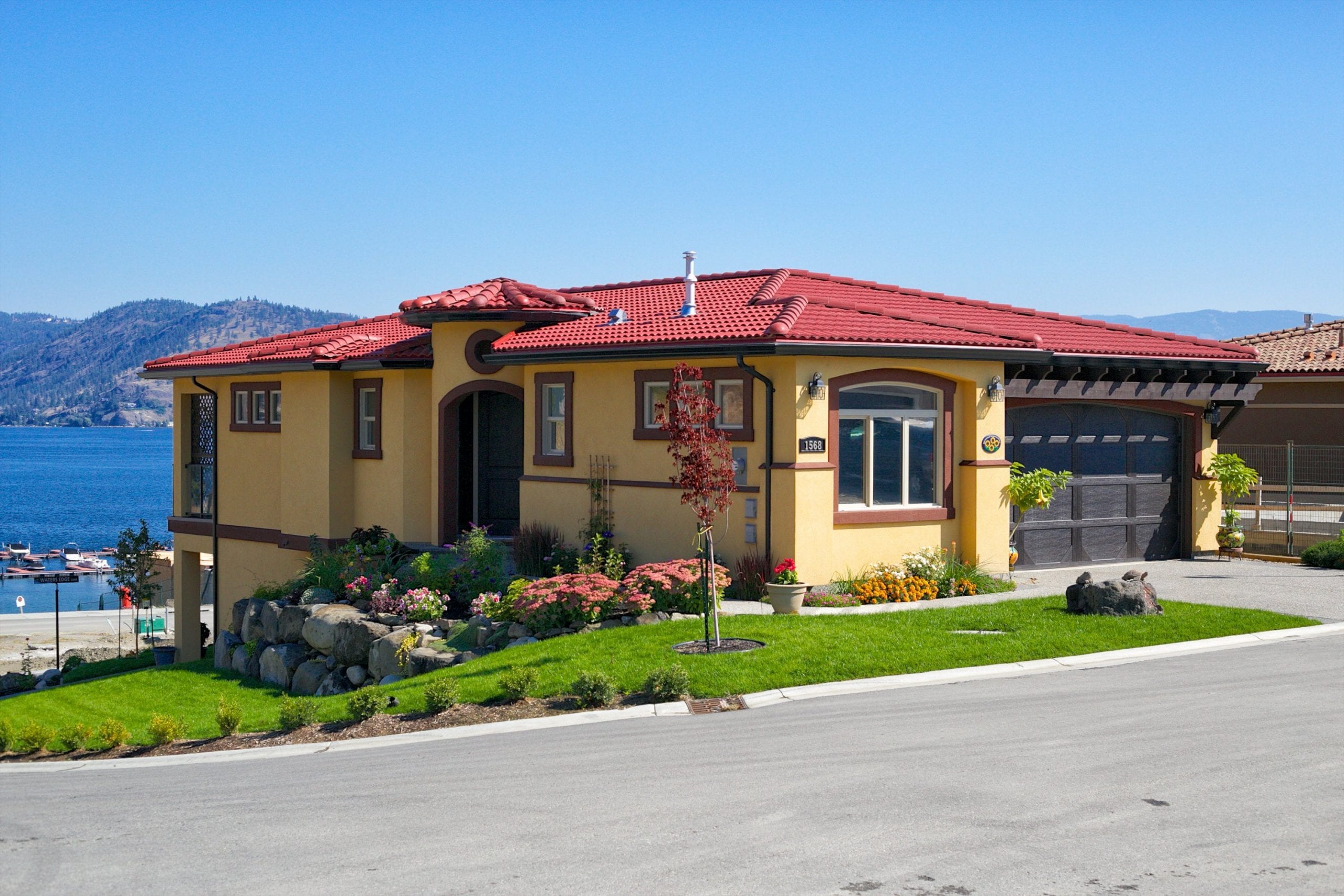 exterior shot of chardonnay roofed home with parmesan main body overlooking okanagan lake on a clear day