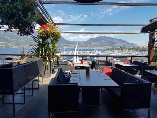 Earls rooftop kelowna nice chairs and tables with houseplant overlooking the docks okanagan lake and the mountains