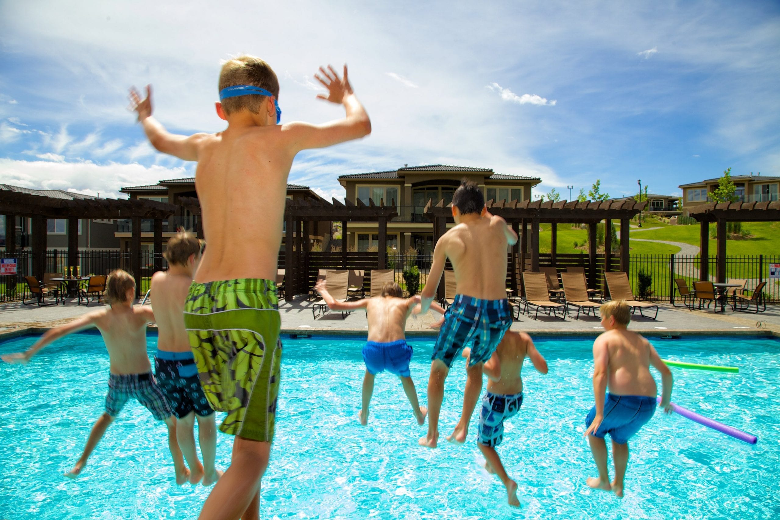 male children in mid air jumping into the harbour club pool on a nice day