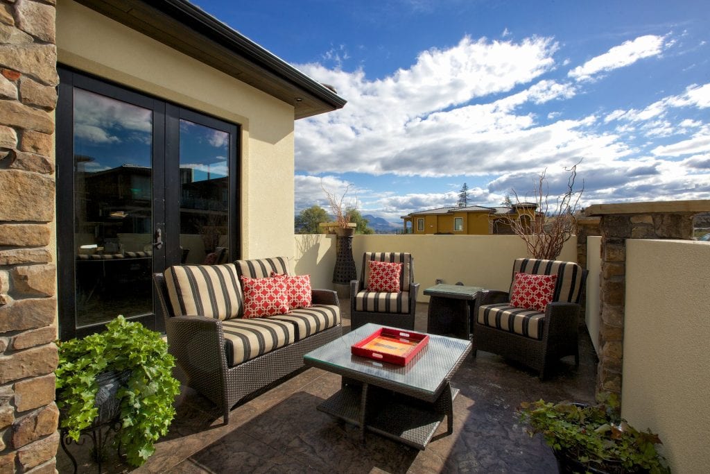 patio shot of west harbour home with beasket weave chairs a table and two houseplants