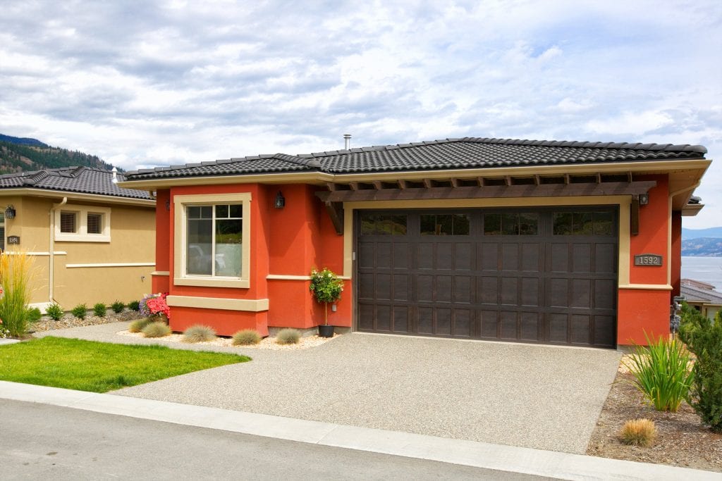 exterior shot of red chianti home with tan details in west harbour overlooking the okanagan lake in the background