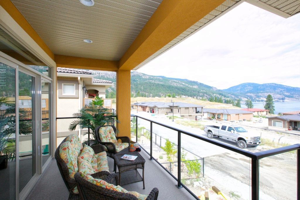 patio shot of west harbour home with three basketweave chairs padded with cushions around a basketweave table