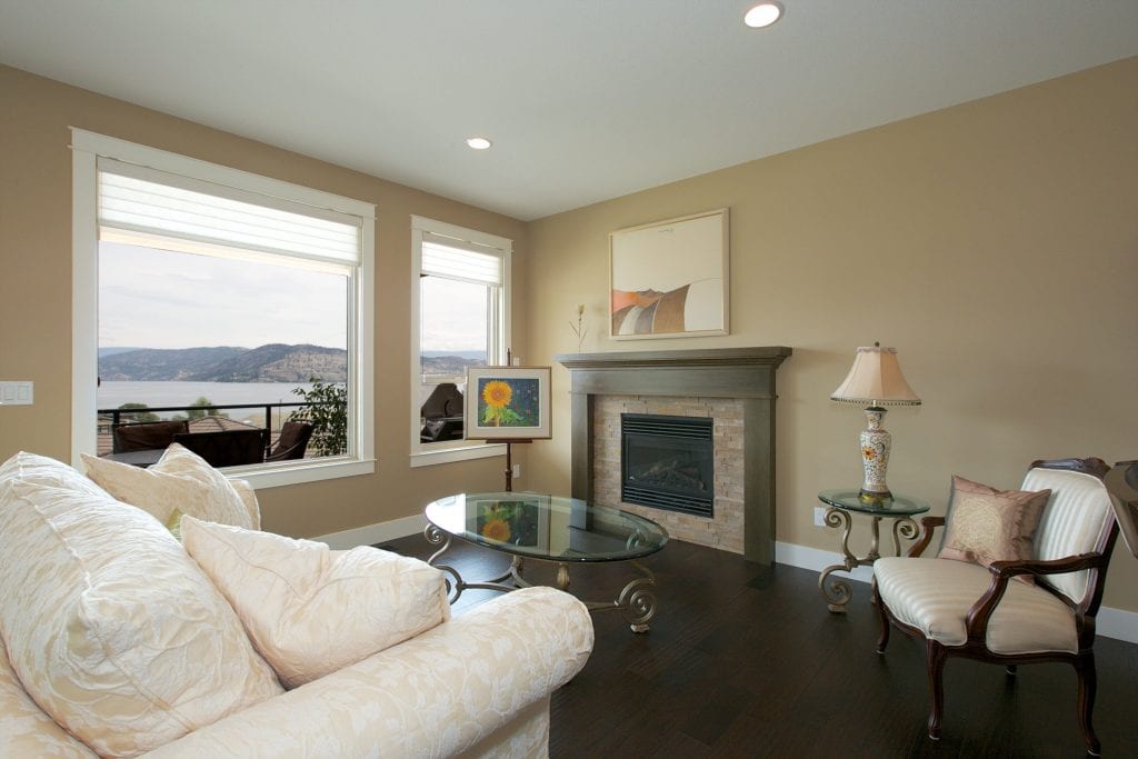 interior shot of west harbour home living space with white couch two tables two lakeview windows and a fireplace