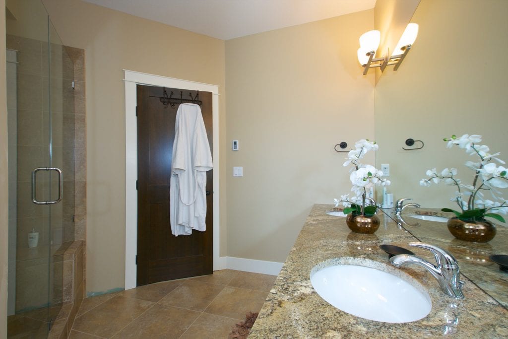 interior shot of west harbour home kitchen with a large mirror a sink and a shower in full view with marble countertops