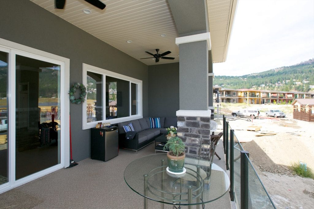 patio shot of west harbour home with houseplant on glass table and large chair with pillows in background