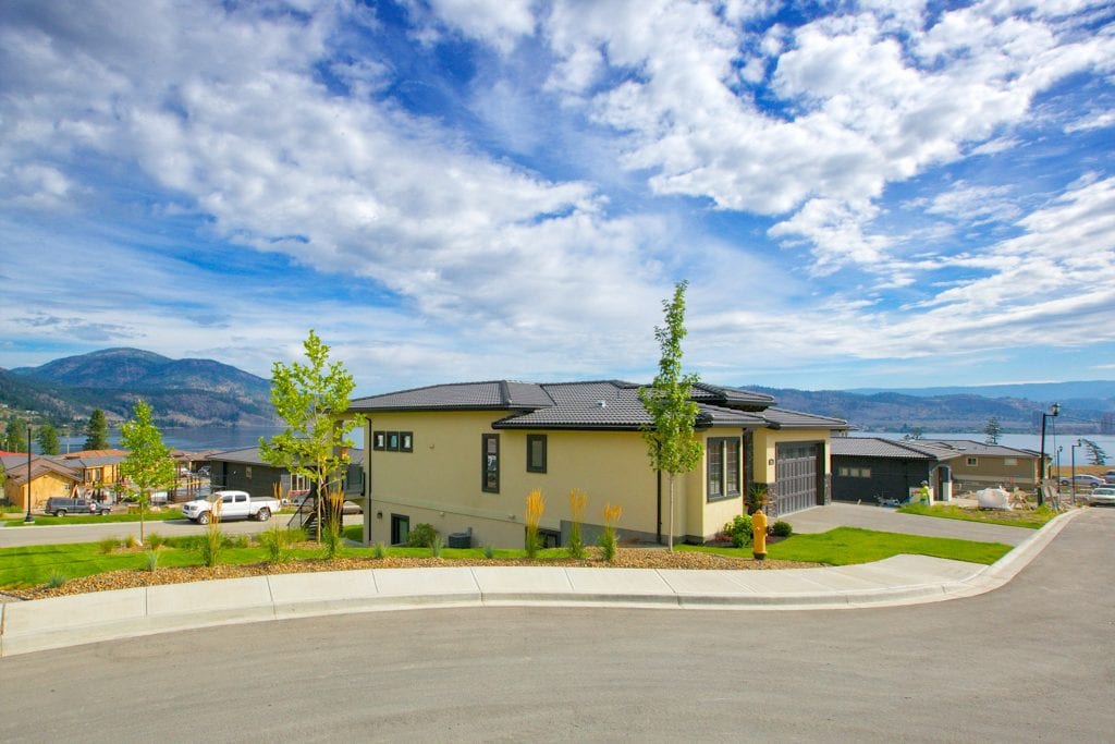 exterior shot of cream coloured west harbour home in the distance with other homes and the lake also in view